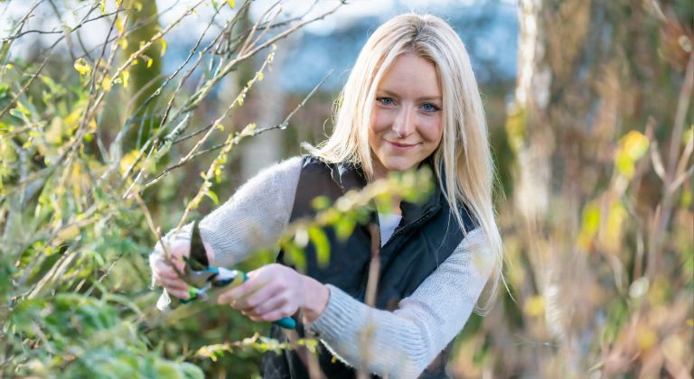 Firefly detaljeret photografi af en ung skandinavisk blondine som beskærer haven i vinterperioden. S copy
